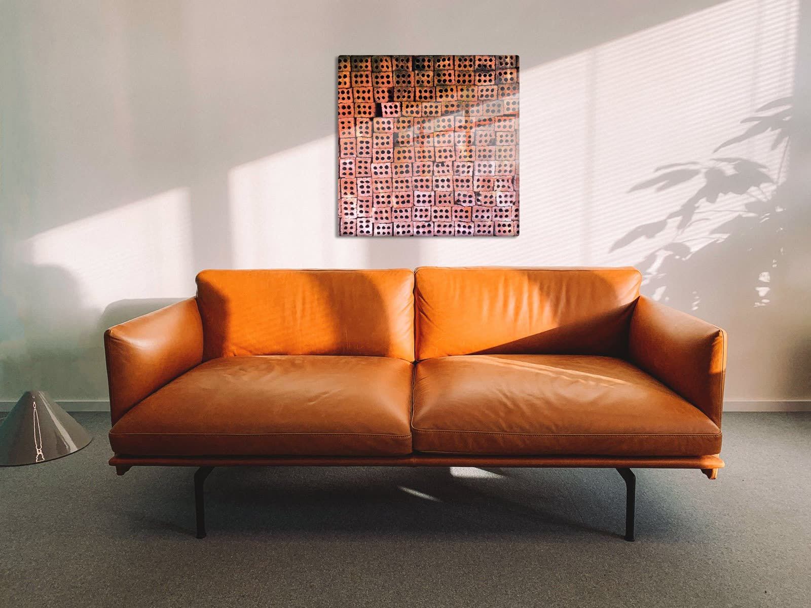 40 inch Patterns of Da Nang aluminum print centered above a cognac leather sofa